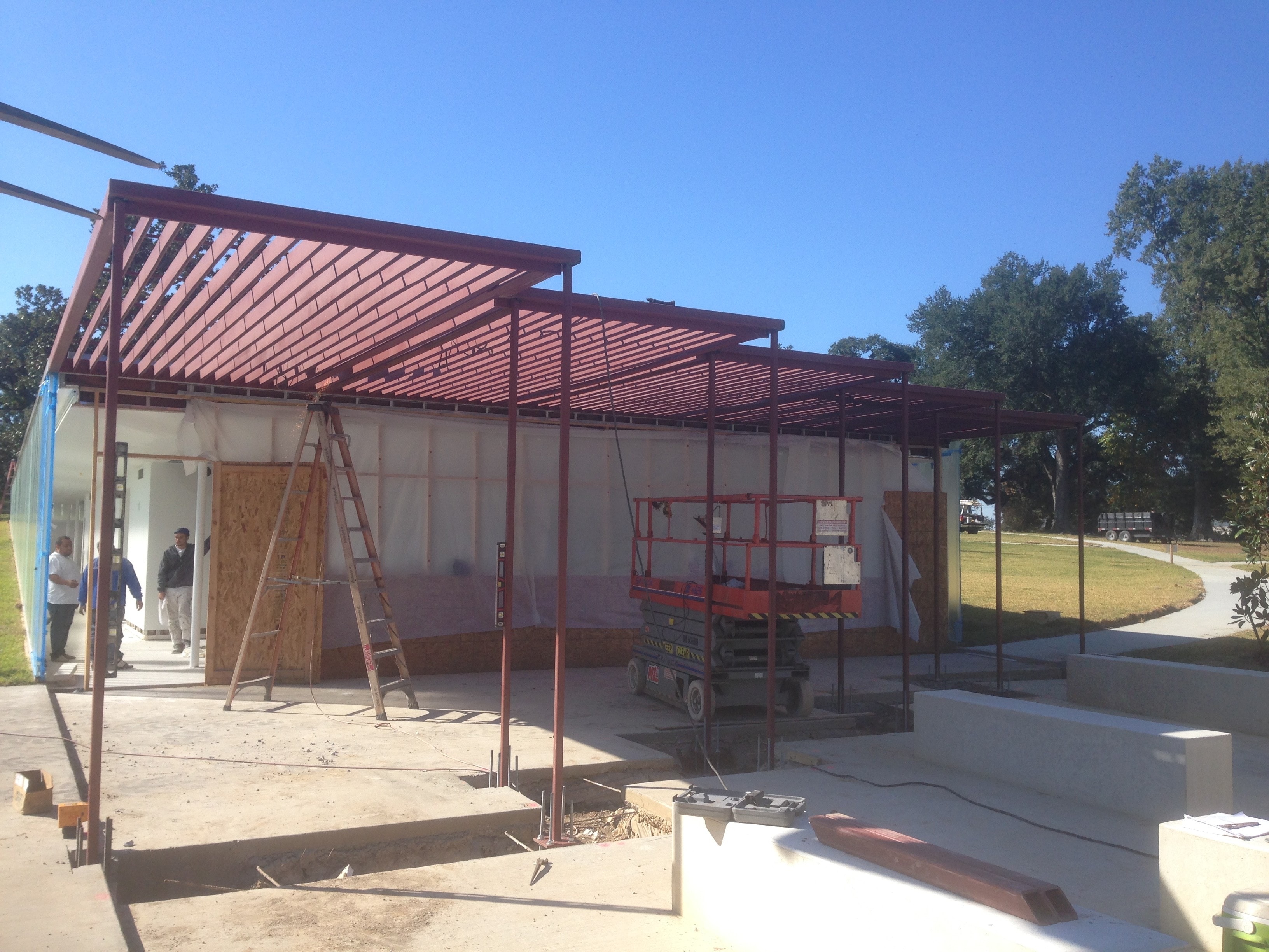 Magnolia Mound structural steel pergola framing under construction with scissor lift