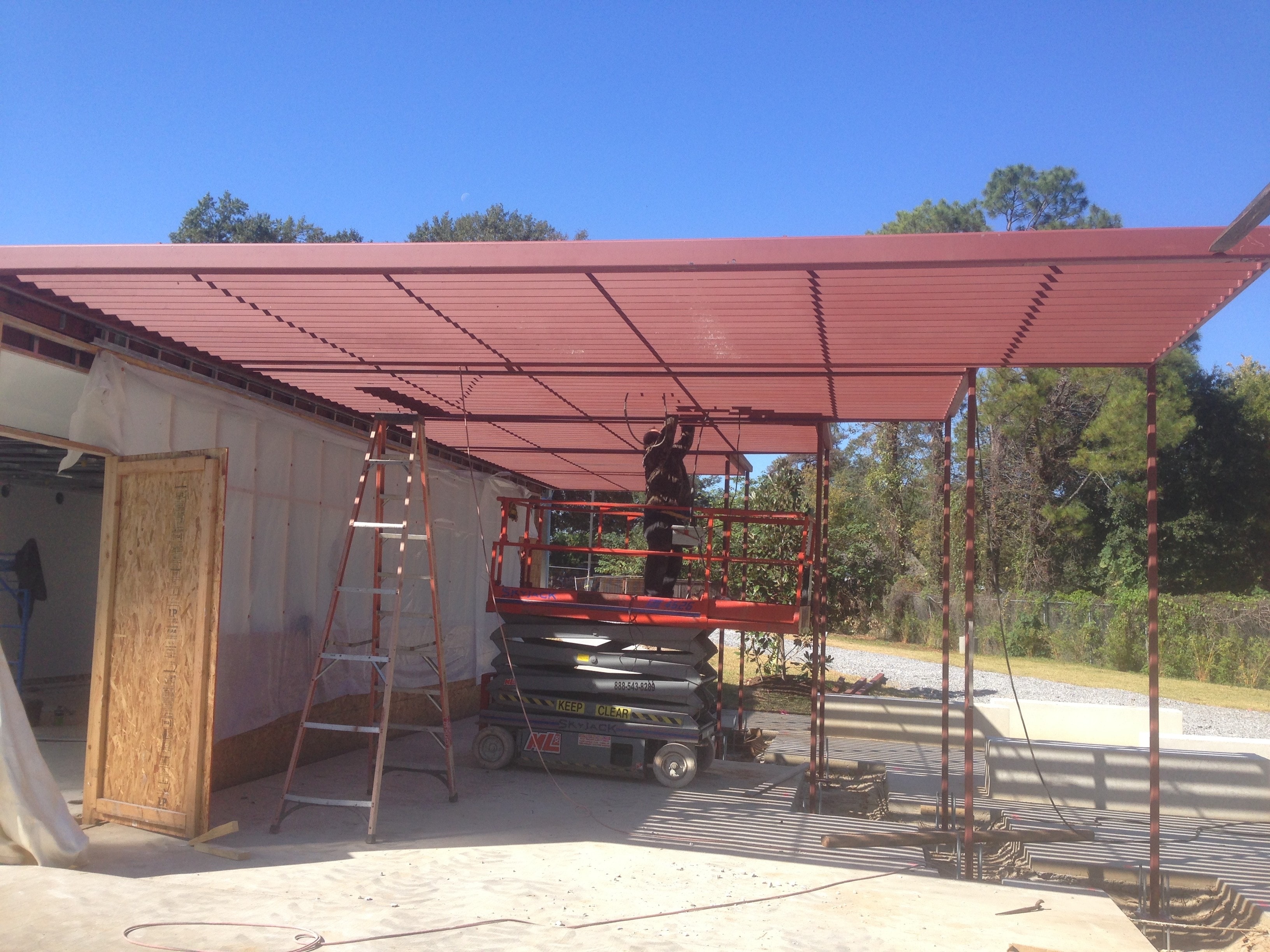 Magnolia Mound steel roof framing with ironworker on scissor lift installing decking