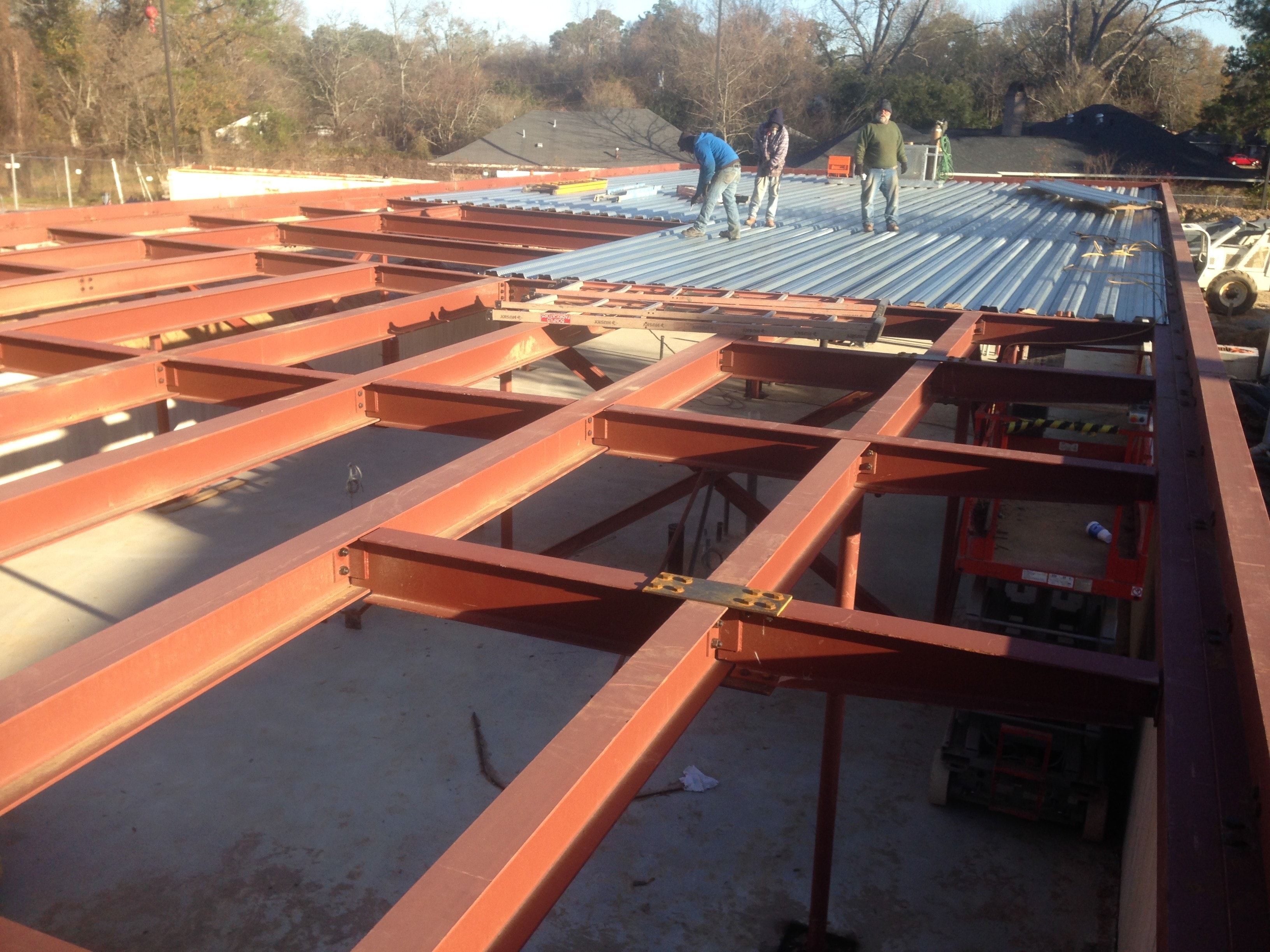 Magnolia Mound steel roof framing with ironworkers installing metal decking from above