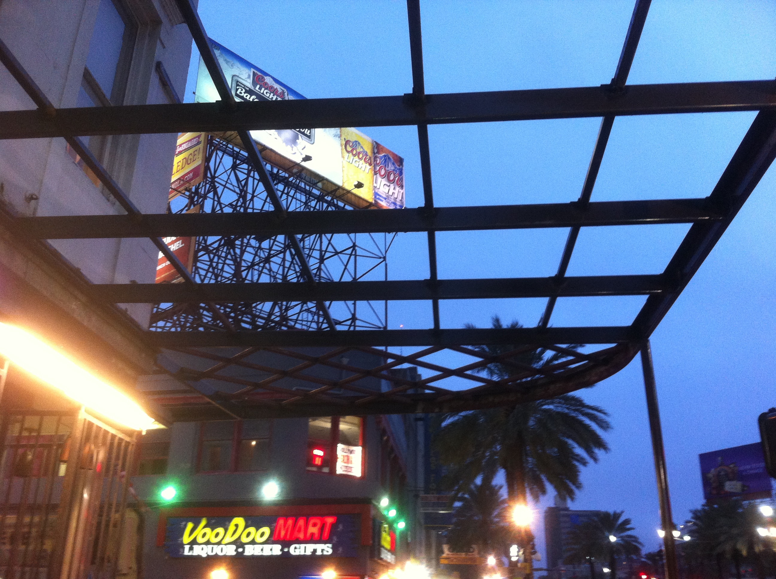 Maison Pierre Hotel canopy steel grid framing viewed from below at dusk showing structural steel members and VooDoo Mart in background