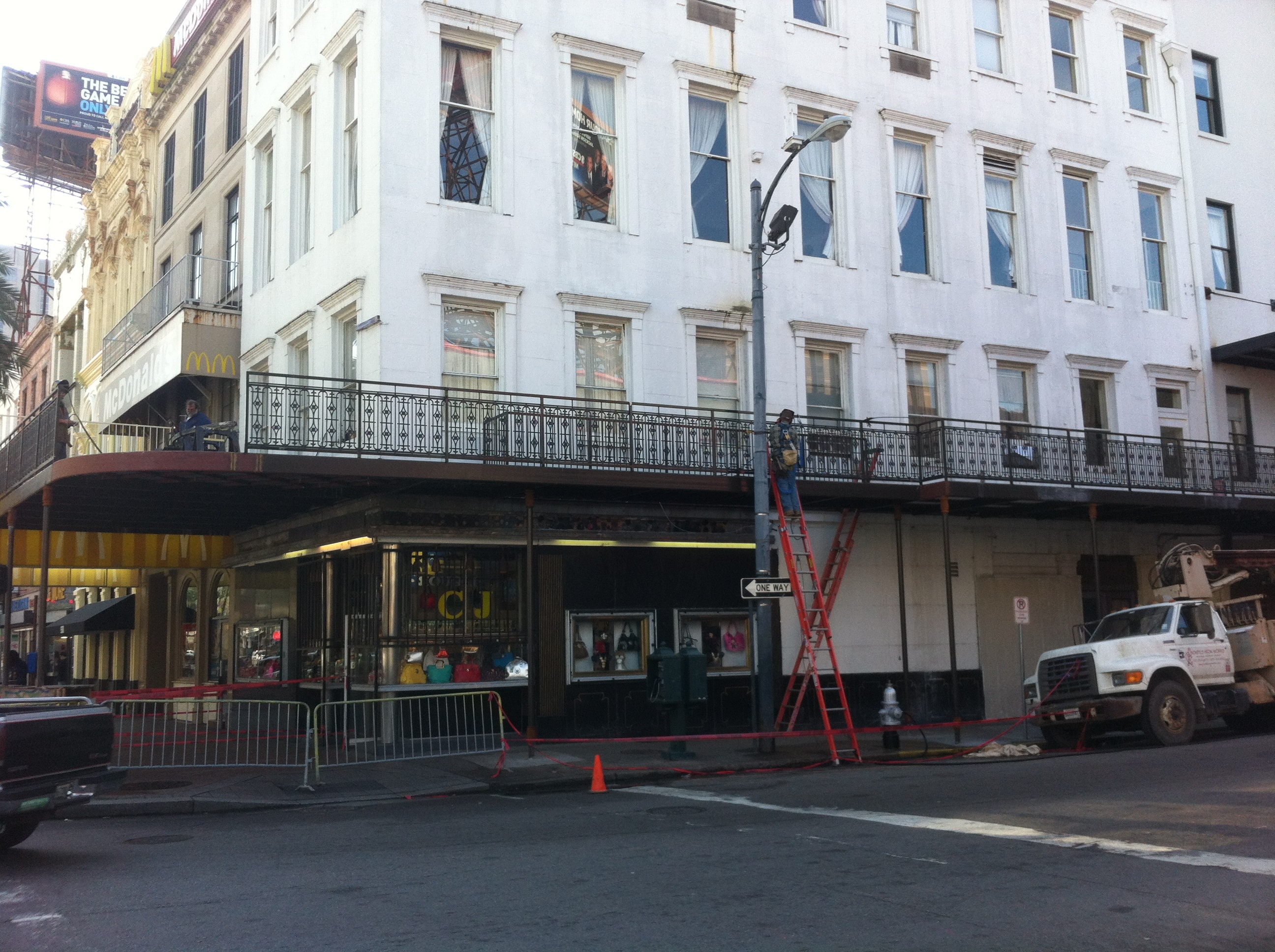 Maison Pierre Hotel street-level view showing first floor balcony steel framing being installed with worker on ladder