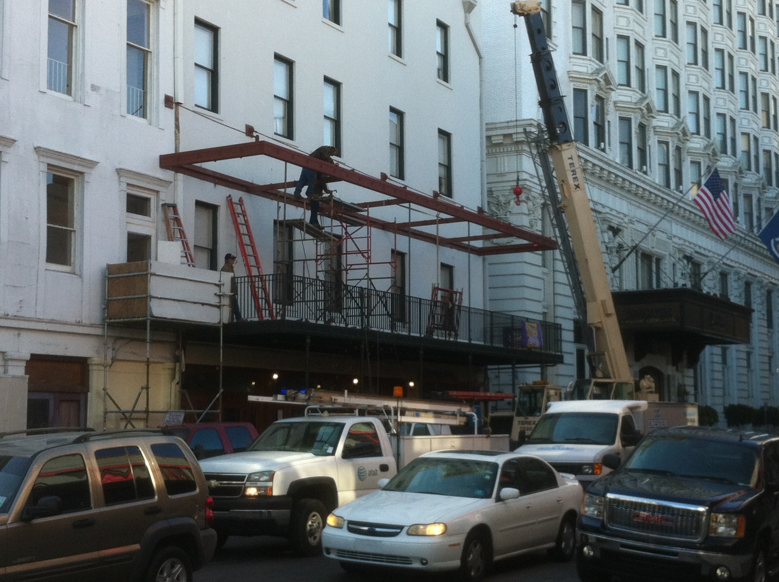 Maison Pierre Hotel upper balcony steel frame being set by Terex crane with ironworkers on scaffolding