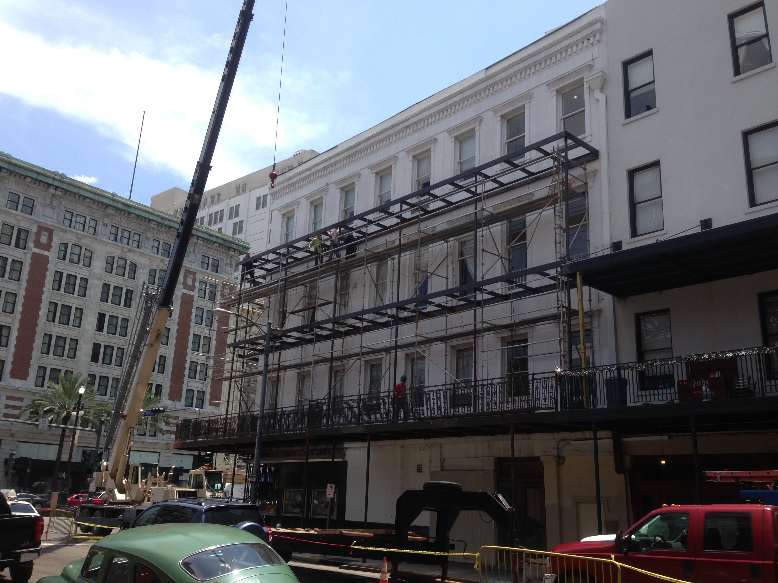 Maison Pierre Hotel upper balcony steel framing being erected with crane and ironworkers on scaffolding along Canal Street