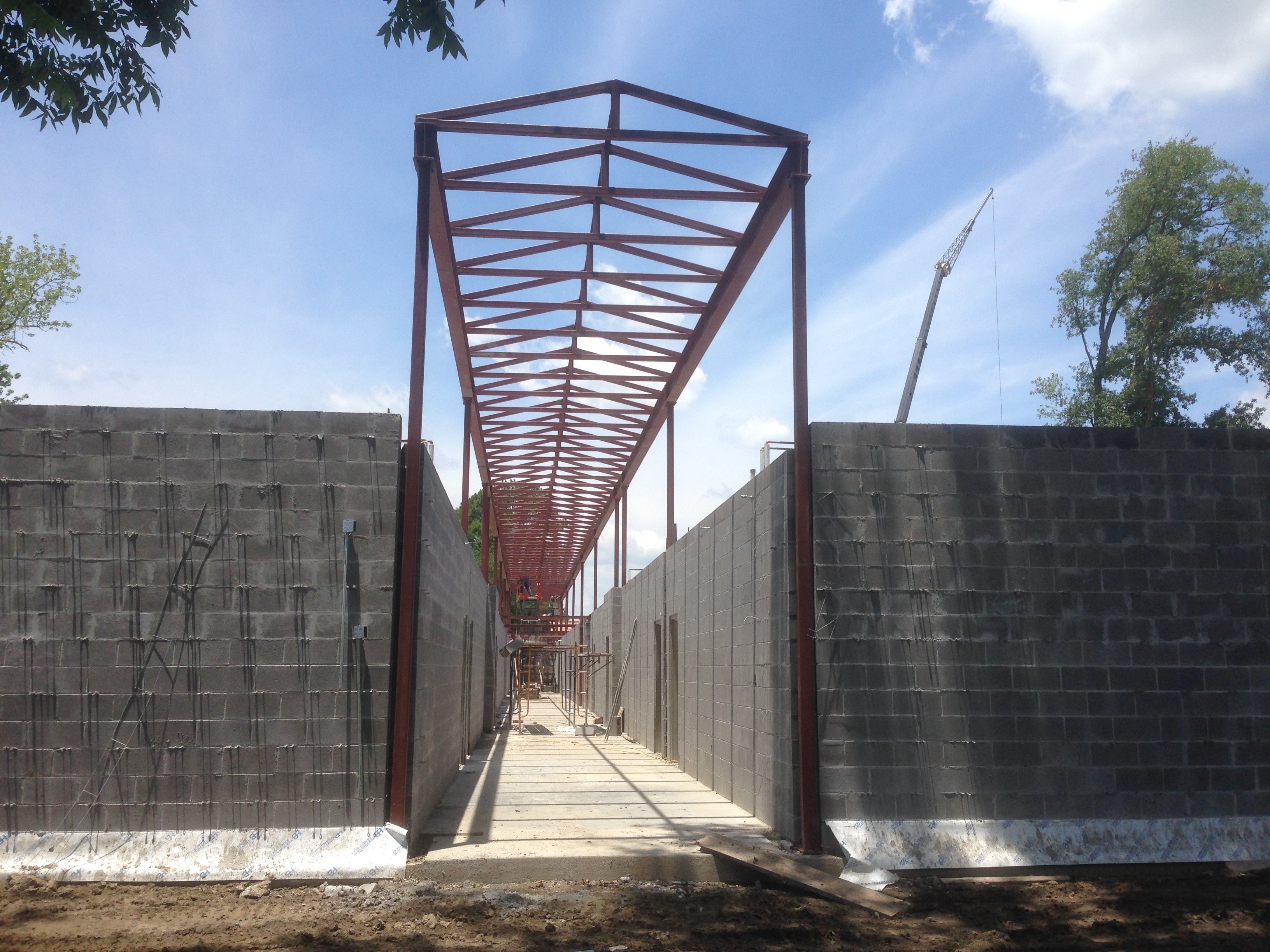 Norco Elementary Addition — red steel roof trusses framing corridor between CMU walls