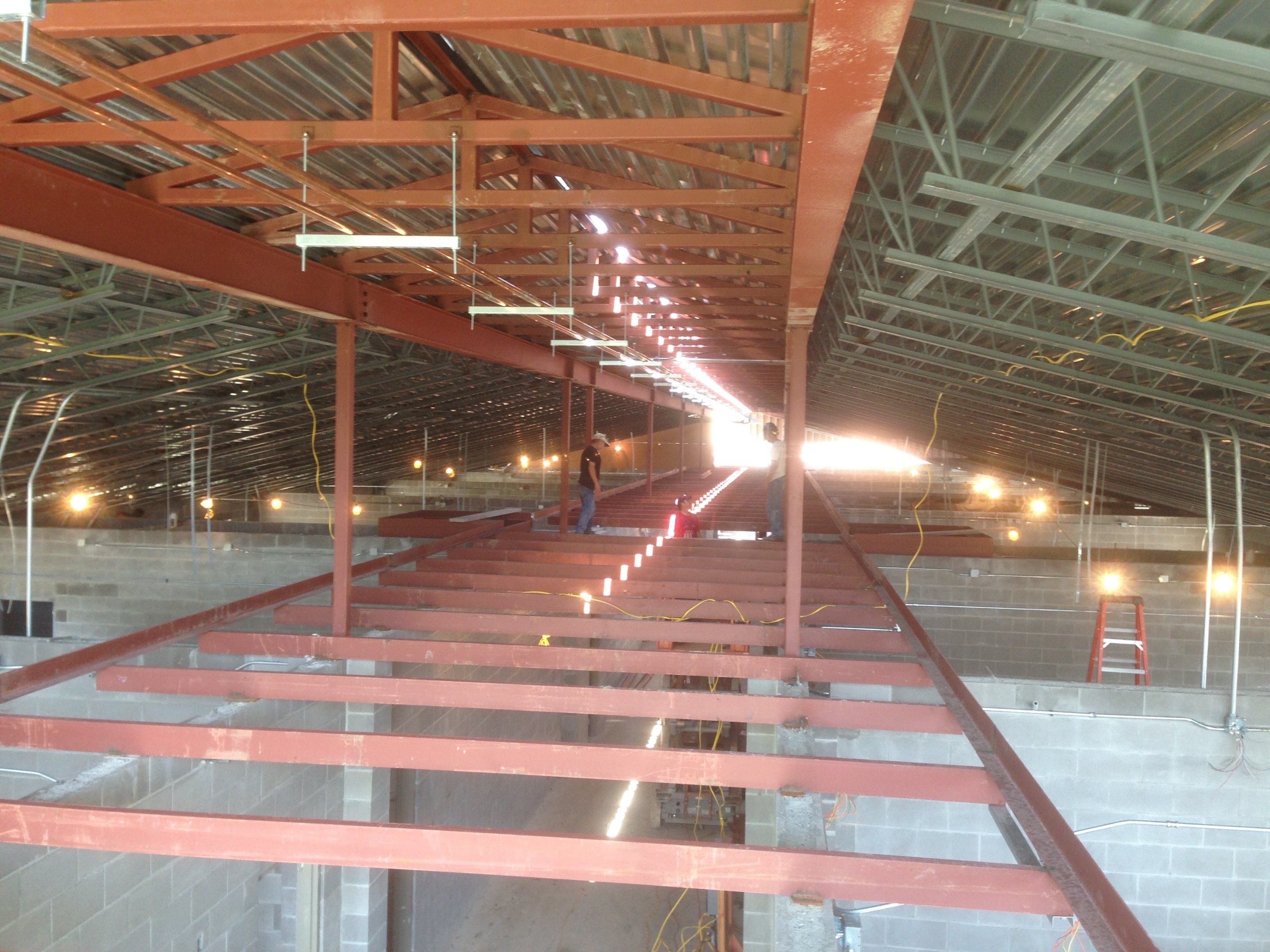 Norco Elementary Addition — interior view of red structural steel beams and bar joist with work lights