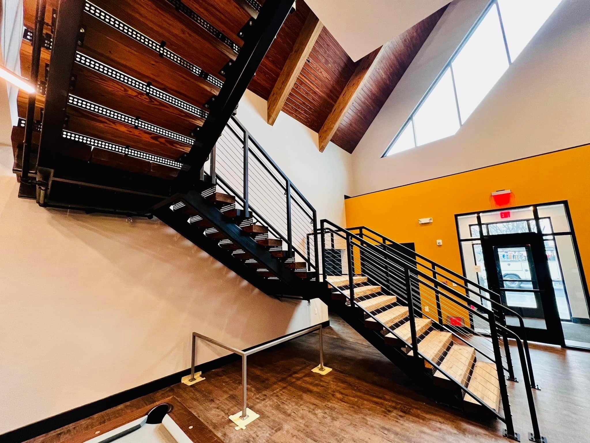 The Clubhouse wide view of entry staircase with orange accent wall and stainless cable railings at ground level