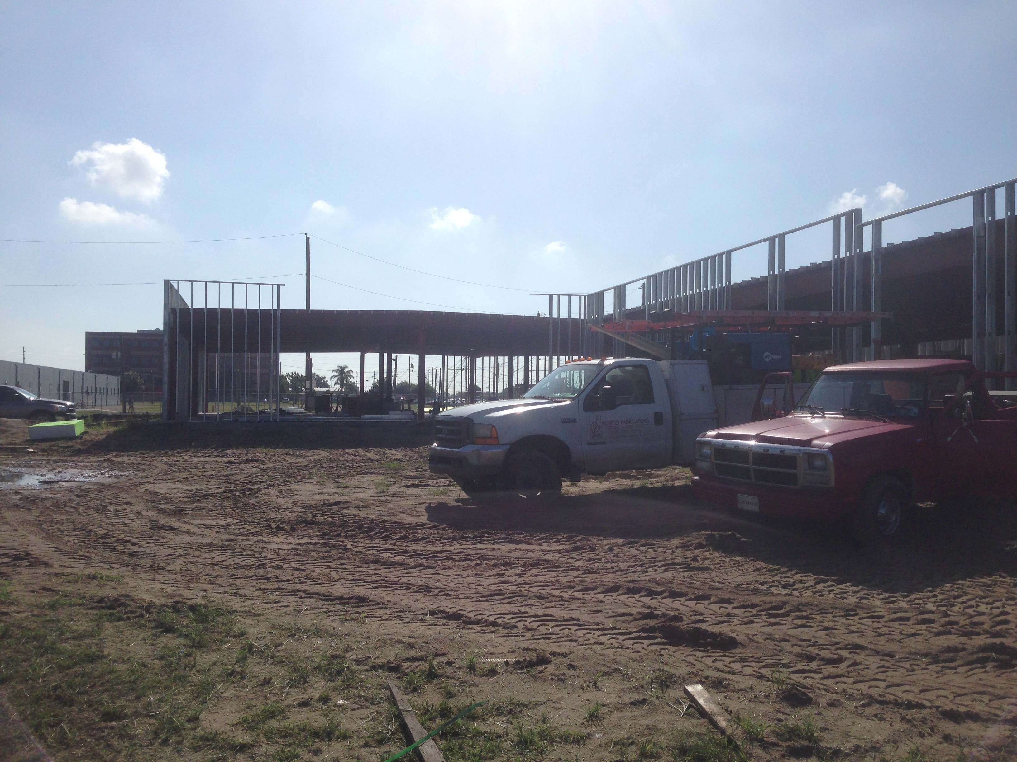 USF Business & Admin Building Addition — stud wall framing and canopy steel with service trucks on site